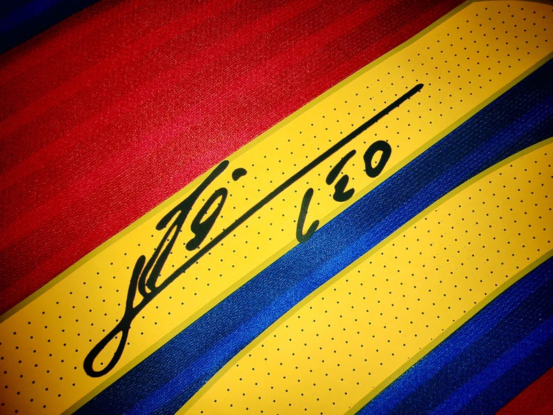 May include: A yellow, blue, and red striped fabric with a black signature that reads "Leo" on it.