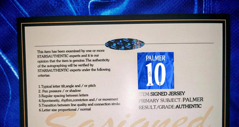 May include: A certificate of authenticity with the text "PALMER 10" on a blue patch, indicating a signed jersey. The certificate is framed with a black border and includes details about the item's verification process.