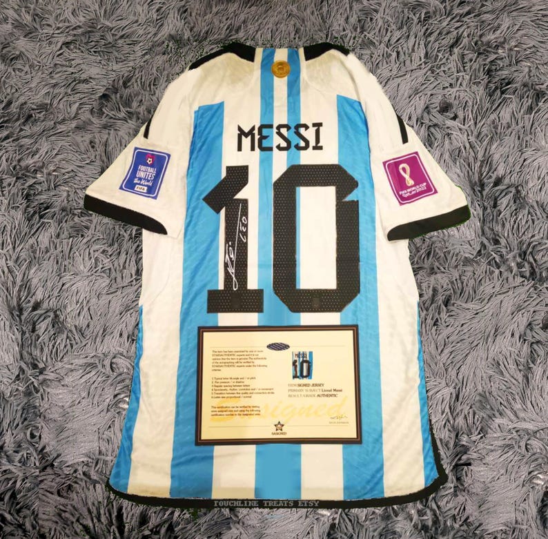 May include: Argentina soccer jersey with the name "MESSI" and the number "10" on the back. The jersey is white and light blue striped with black trim. Includes a certificate of authenticity and a signature.