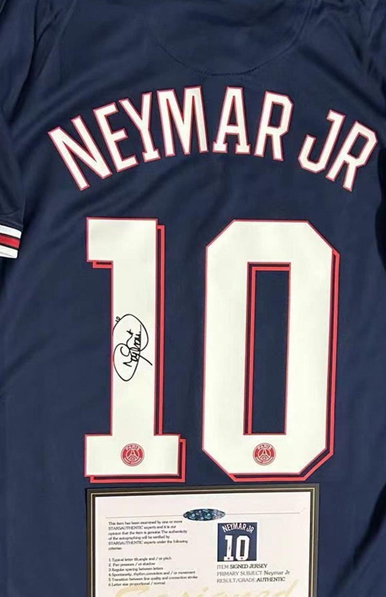 May include: Navy blue jersey with the name "NEYMAR JR" arched across the back in white lettering. The number "10" is prominently displayed in white with red trim. Includes a signature and a certificate of authenticity.
