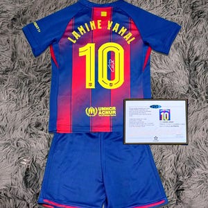 May include: A blue and red soccer jersey and shorts set. The jersey features the name "LAMINE YAMAL" and the number "10" in yellow. The set includes a certificate of authenticity.