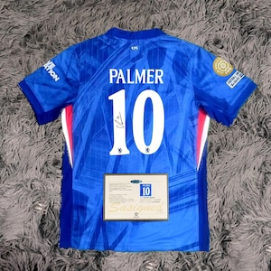 May include: A blue soccer jersey with the name "PALMER" and the number "10" printed on the back. The jersey has a signature and a certificate of authenticity. The jersey has white and red accents.
