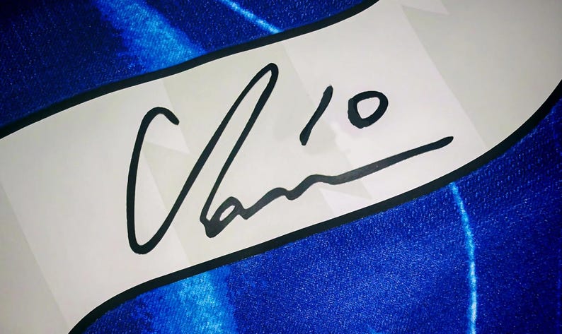 May include: A white banner with a black border displays a signature and the number 10 in black ink. The banner is set against a textured blue background, creating a contrast between the white and blue.