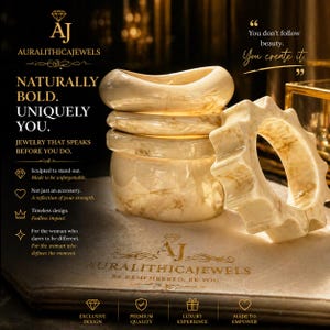 Op de afbeelding: Een verzameling crèmekleurige, gemarmerde stenen armbanden, waarvan één met een uniek, getextureerd ontwerp. De afbeelding toont de tekst "AURALITHICAJEWELS" en de quote "You don't follow beauty. You create it."