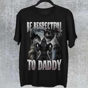 May include: Black t-shirt with a graphic of werewolves under a full moon. The design includes the text "BE RESPECTFUL TO DADDY" in a stylized font. The image has a fantasy theme.