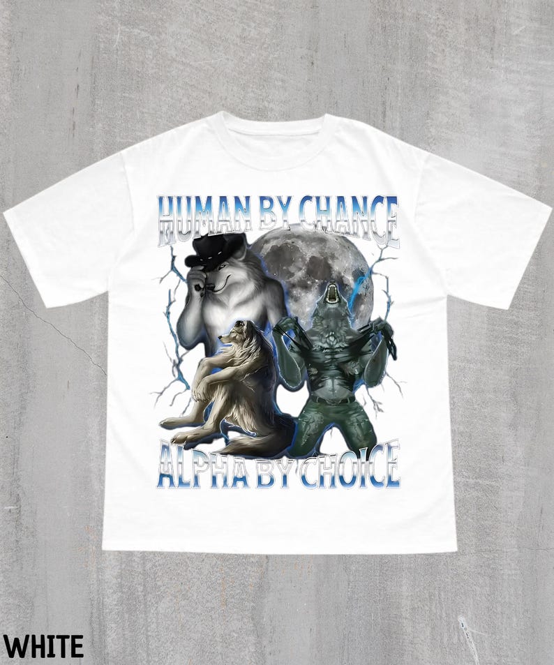 May include: White t-shirt featuring a graphic design with the text "HUMAN BY CHANCE" and "ALPHA BY CHOICE" in blue. The design includes illustrations of a wolf wearing a hat, a wolf, and a creature in front of a full moon.