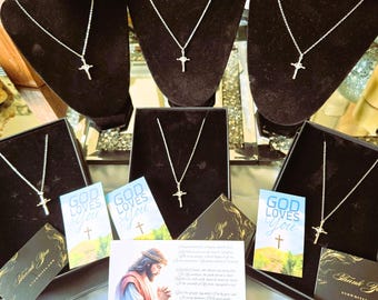 May include: Silver cross necklaces displayed on black velvet busts and in black boxes. The image includes cards with the text "GOD LOVES YOU" and a portrait of Jesus. Also included are "Thank You" cards.