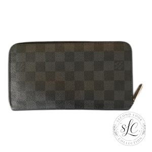 May include: A white ceramic mug with a black handle and the text "But First, Coffee" in a bold, black font. The mug is set against a blurred background, suggesting a cozy setting.