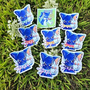 May include: A collection of stickers featuring a blue cat with an angry expression, wearing a spiked collar. The stickers are on a bed of green grass. One sticker has the text "THIS CATS ARE HUMAN RIGHTS".
