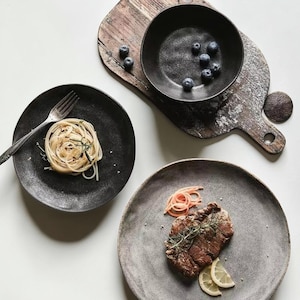 Pode incluir: Uma tábua de cortar de madeira feita à mão com um acabamento natural. A tábua apresenta uma borda viva de um lado e uma forma retangular lisa. Tem aproximadamente 45 cm de comprimento e 30 cm de largura.