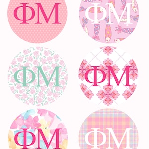 May include: A collection of six circular designs with the Greek letters ΦΜ. Each circle features a different pattern, including polka dots, fish, floral, and plaid. The letters are in various colors, such as pink, white, and teal, against a pastel background.