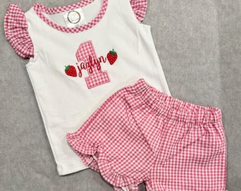 Mono de burbuja bordado para el primer cumpleaños con fresas y volantes de cuadros vichy.