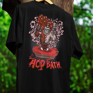 May include: Black t-shirt with a graphic of a clown-like figure with a skull head, in a red acid bath. The clown has a mushroom-shaped headpiece. The words "ACID BATH" are printed in red below the image.