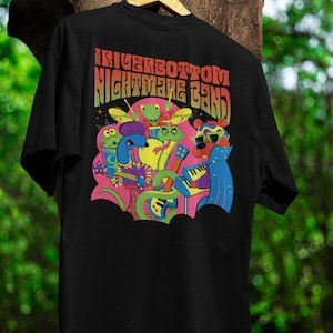 May include: Black t-shirt featuring a colorful graphic of a band of cartoon animals playing instruments. The text "Riverbottom Nightmare Band" is arched across the top. The design includes a bear, snakes, frogs, and other creatures.