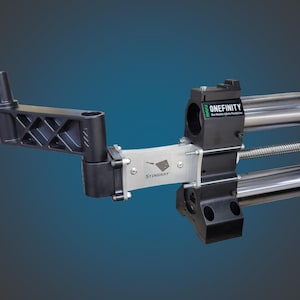 May include: A black and silver machine component with the text "ONEFINITY" and "STINGRAY". The component has a complex design with multiple arms and cylindrical metal bars. The background is a gradient of blue.