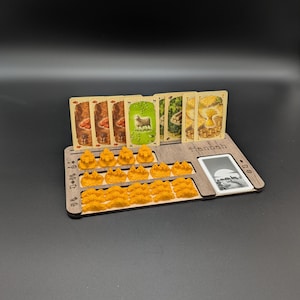 May include: A wooden game organizer with slots for cards and game pieces. The organizer holds several cards with illustrations and orange game pieces. The word "Henbash" is printed on the organizer.