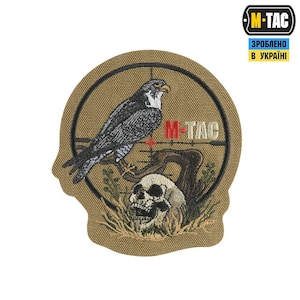 Puede incluir: Un parche bordado de color beige con un halcón posado en una rama con una calavera en la base. El parche tiene una cruz roja y el texto "M-TAC" en rojo y negro. El texto "ЗРОБЛЕНО В УКРАЇНІ" está en azul y negro.
