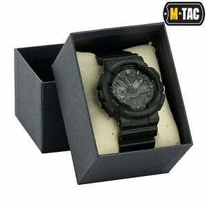 May include: A black digital watch with a black band is displayed inside a gray gift box. The watch face shows the time and has multiple dials and buttons. The box is open, revealing the watch resting on a cream-colored cushion. The watch is water resistant.