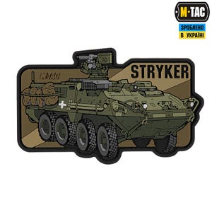 May include: A green and brown military vehicle with the text "STRYKER" printed on the side. The vehicle has a large cannon on top and is on a brown background. The text "M-TAC" is printed in the top right corner of the image.