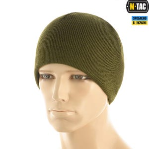 May include: Olive green knit beanie. The hat is made of a ribbed knit fabric and has a rounded crown. The M-TAC logo and "Made in Ukraine" text are visible in the upper right corner.