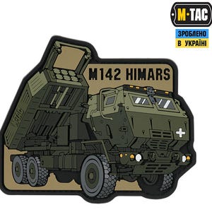 Könnte beinhalten: Ein beige-grüner Patch mit einer Cartoon-Illustration eines Militärfahrzeugs, dem M142 HIMARS, mit dem Text "M142 HIMARS" und "M-TAC" in Schwarz. Der Text "ЗРОБЛЕНО В УКРАЇНІ" ist in Blau und Gelb.