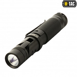 Op de afbeelding: Zwarte zaklamp met een getextureerde grip en een zakclip. De zaklamp heeft een helder LED-licht en het M-TAC-logo is zichtbaar. De cilindrische zaklamp lijkt van metaal te zijn.
