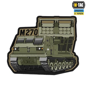 Puede incluir: Un parche con una ilustración detallada de un Sistema de Lanzamiento Múltiple de Cohetes M270 (MLRS) en tonos verdes y marrones. El parche incluye el texto "M270", el logotipo M-TAC y texto en ucraniano.