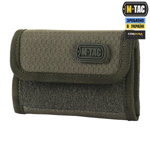May include: Olive green tactical pouch with a hexagonal pattern on the flap. The pouch has a hook-and-loop closure and a black border. The M-TAC logo is visible on the front. The pouch is made of Cordura fabric.