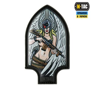 May include: A patch depicting a warrior woman with blonde braids, a helmet, and wings, holding a rifle. The design includes a pistol, ammunition belt, and a black border. The M-TAC logo and Ukrainian text are visible.