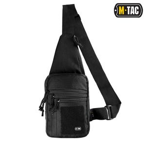 Könnte beinhalten: Schwarze Umhängetasche mit verstellbarem Schultergurt. Sie verfügt über mehrere Reißverschlussfächer, einen Klettverschluss und das M-TAC-Logo. Die Tasche ist für das Tragen über dem Körper konzipiert.