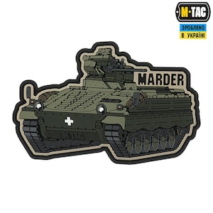 May include: A black and green Marder infantry fighting vehicle with the text "Marder" in white letters. The vehicle has a white cross on the front and is on a tan background.