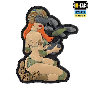 Könnte beinhalten: Ein Patch mit einer Frau in Tarnkleidung, die einen Drohnen-Controller hält. Die Drohne fliegt über ihr. Der Patch ist schwarz und trägt den Text "M-TAC" und "ЗРОБЛЕНО В УКРАЇНІ".