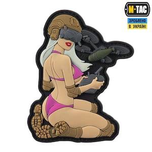 May include: A patch depicting a cartoon woman in a pink bikini and a military helmet, controlling a drone. The patch has a black border and includes the M-TAC logo and Ukrainian text.