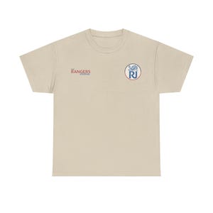 May include: A beige t-shirt featuring the text "The Rangers Journal" in red and a circular emblem with "RJ" in blue. The emblem is surrounded by a white and blue design. The shirt has a crew neck and short sleeves.