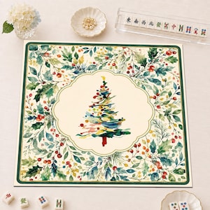 May include: A square mat featuring a watercolor-style Christmas tree in the center, surrounded by a decorative border of green holly leaves and red berries. The design is set against a cream background with a dark green frame around the edge.