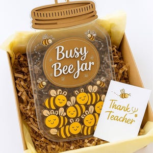 May include: A gift box with a jar-shaped design, featuring the text "Busy Bee Jar" and bee illustrations. The box includes a card that says "Thank You Teacher". The jar is filled with yellow and black bees.