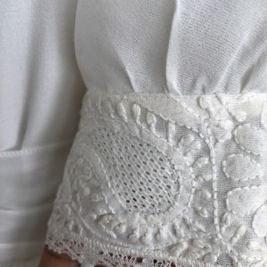 May include: White cotton fabric with a delicate lace trim. The lace features a floral pattern and is sewn onto the edge of the fabric.