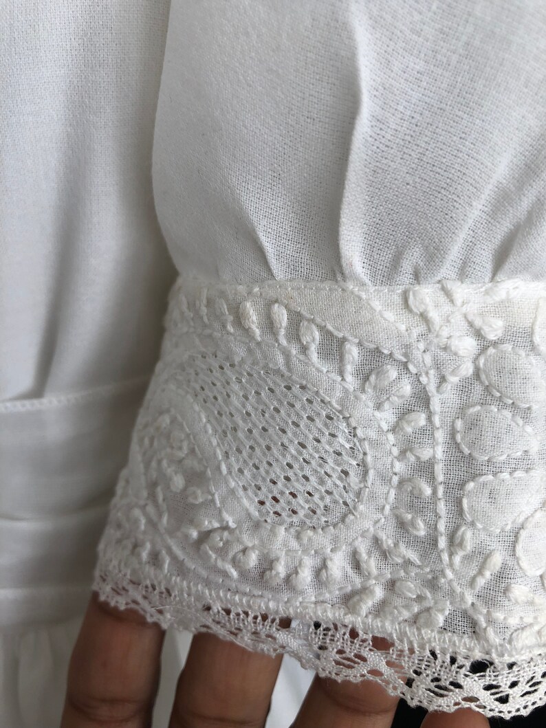May include: White cotton fabric with a delicate lace trim. The lace features a floral pattern and is sewn onto the edge of the fabric.