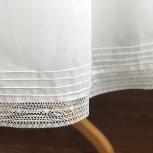 May include: White cotton skirt with a lace trim and three rows of stitching around the hem.