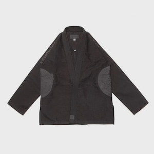 Könnte beinhalten: Schwarzer Jiu-Jitsu-Gi mit V-Ausschnitt und verstärkten Knielappen. Der Gi hat den Text "x Cunian" auf der linken Schulter aufgedruckt. Der Gi liegt flach auf weißem Hintergrund.