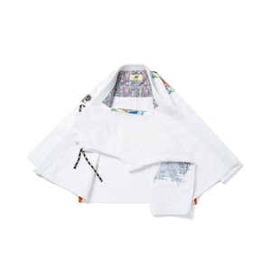 May include: White martial arts uniform with colorful patterned collar lining and accents. The uniform includes a jacket and pants. The jacket has a black and yellow rope detail and a blue geometric design on the pants.