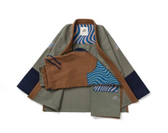 May include: Olive green martial arts uniform with brown trim and navy blue accents. The uniform includes a jacket and trousers. The jacket features a wave pattern in blue and tan. The uniform has a logo patch.