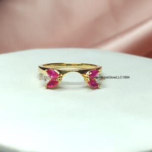 Puede incluir: Anillo de oro con un delicado diseño abierto que presenta dos piedras de rubí en forma de marquesa y dos diamantes blancos más pequeños.