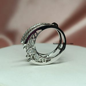 Puede incluir: Un anillo de plata con un dise&ntilde;o delicado e intrincado que presenta peque&ntilde;as piedras transparentes. El anillo tiene un dise&ntilde;o curvo y calado con un motivo floral.