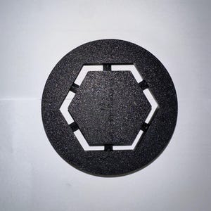 May include: Black plastic hexagonal shaped ring with a textured surface.