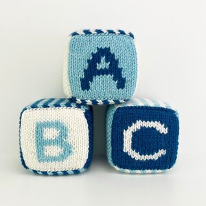 Può includere: Tre blocchi di maglia con le lettere A, B e C su di essi. I blocchi sono blu e bianchi con un motivo a righe.