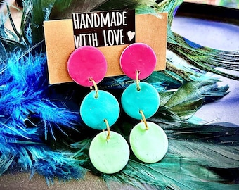 May include: Handmade earrings with a pink, turquoise, and light green color scheme. The earrings are made of polymer clay and have a layered design. The earrings are on a white background with a sign that says "Handmade with Love".