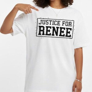 May include: White t-shirt with the text "JUSTICE FOR RENEE" in a black, distressed font inside a black rectangle. The shirt is a simple, casual style.