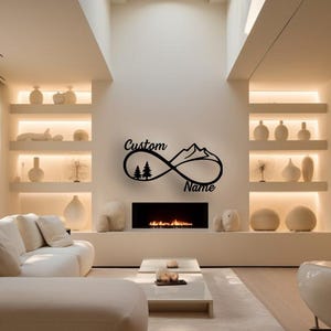 Könnte beinhalten: Ein modernes Wohnzimmer mit weißem Sofa, Couchtisch und Kamin. Ein schwarzes Metall-Wandkunstwerk in Form eines Unendlichkeitssymbols mit Bergen und Bäumen ist über dem Kamin angebracht. Der Text "Custom Name" ist enthalten.