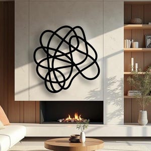 Puede incluir: Un salón moderno presenta una escultura de pared de metal negro con un diseño abstracto. La escultura está montada en una pared de color claro sobre una chimenea con fuego. Una mesa de centro de madera y un sofá blanco están en primer plano.